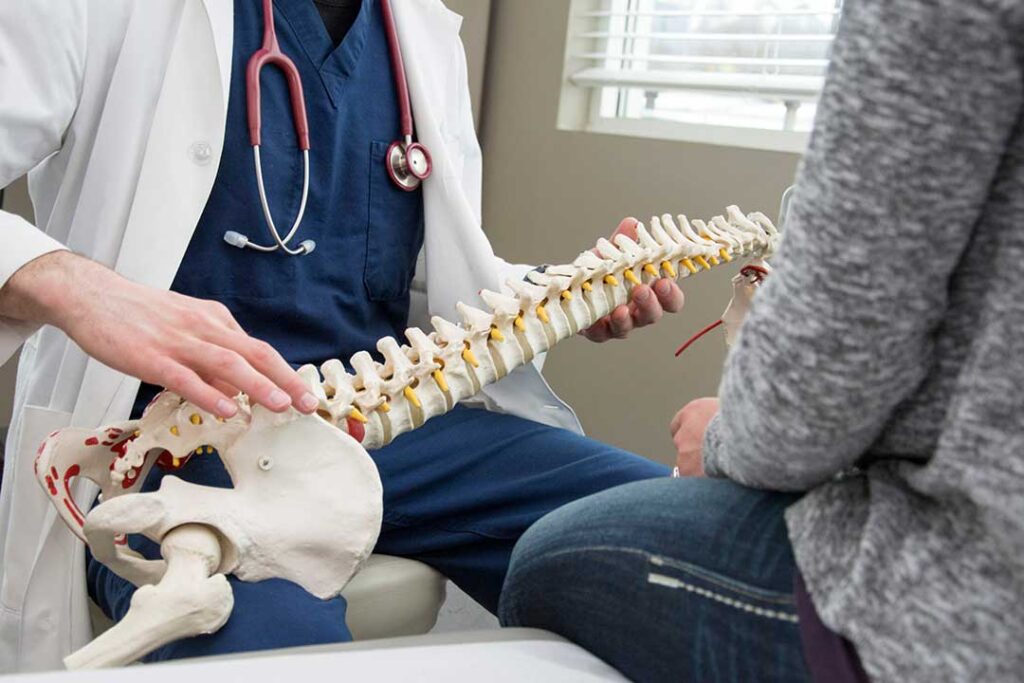 Adult carefully performing gentle back stretches on a living room floor beside a supportive chair.
