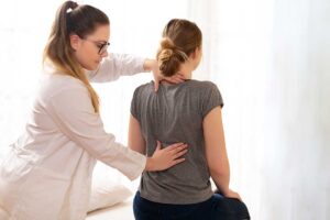 Adult receiving a posture assessment while discussing exercise and daily movement with a healthcare provider.