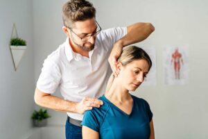 A chiropractor gently adjusts a patient's middle back while the person lies on a padded treatment table.